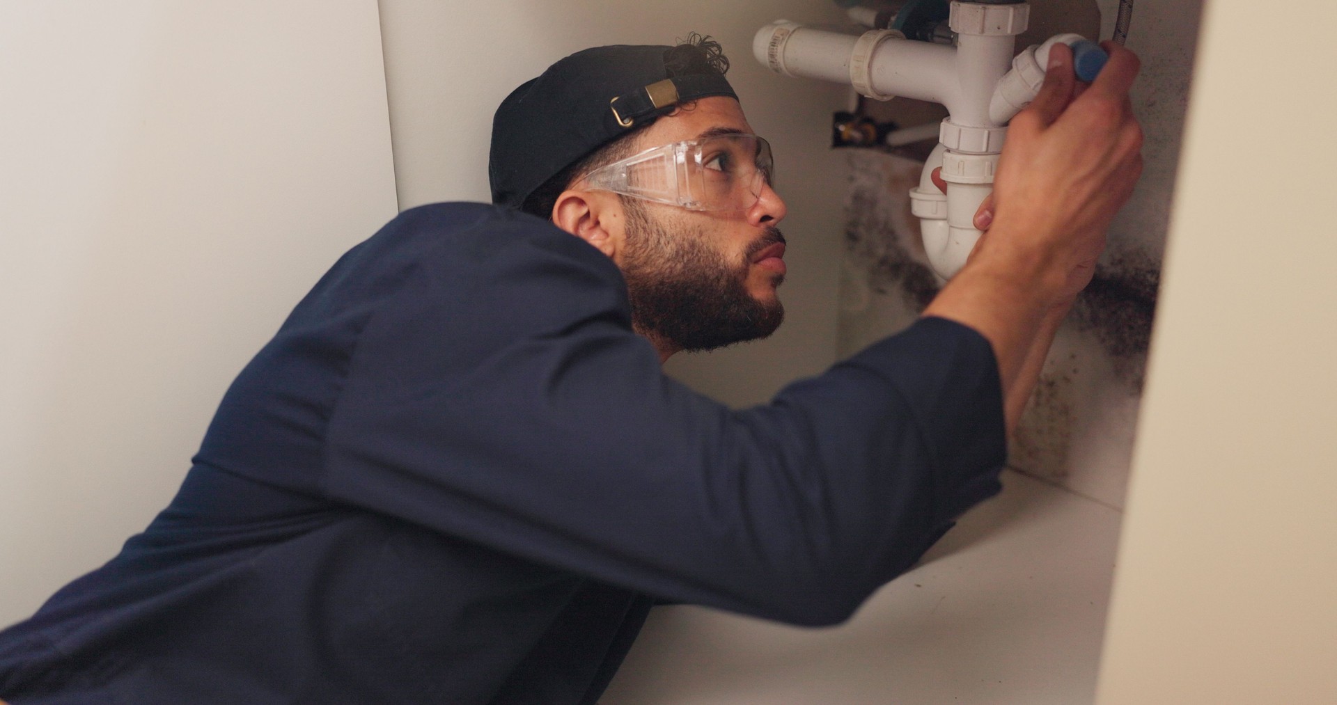 Plumber, man and pipeline repair in kitchen with tools for home maintenance and fixing leak by sink. Plumbing contractor, handyman and working on filter system improvement for small business in house